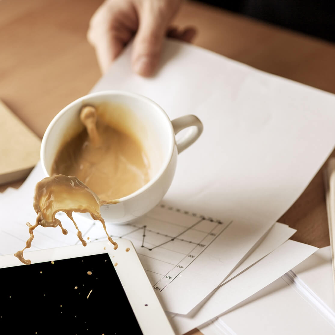 Kiömlött kávé papírokon és egy tableten